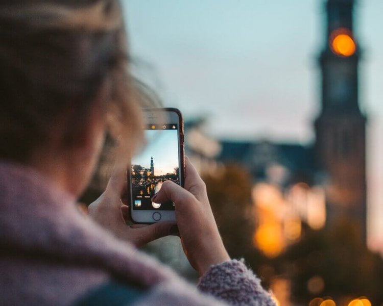 a student using her phone to take a picture of a building in the distance