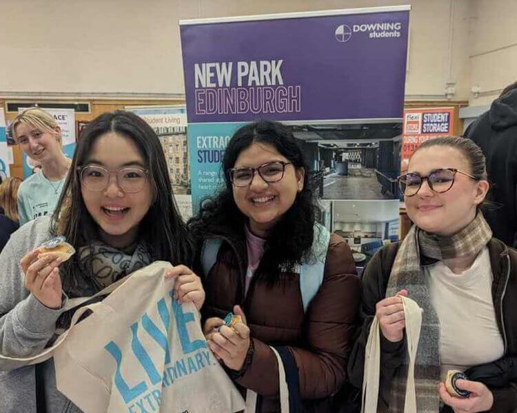 image of three students holding downing student goodie bags at a student fair